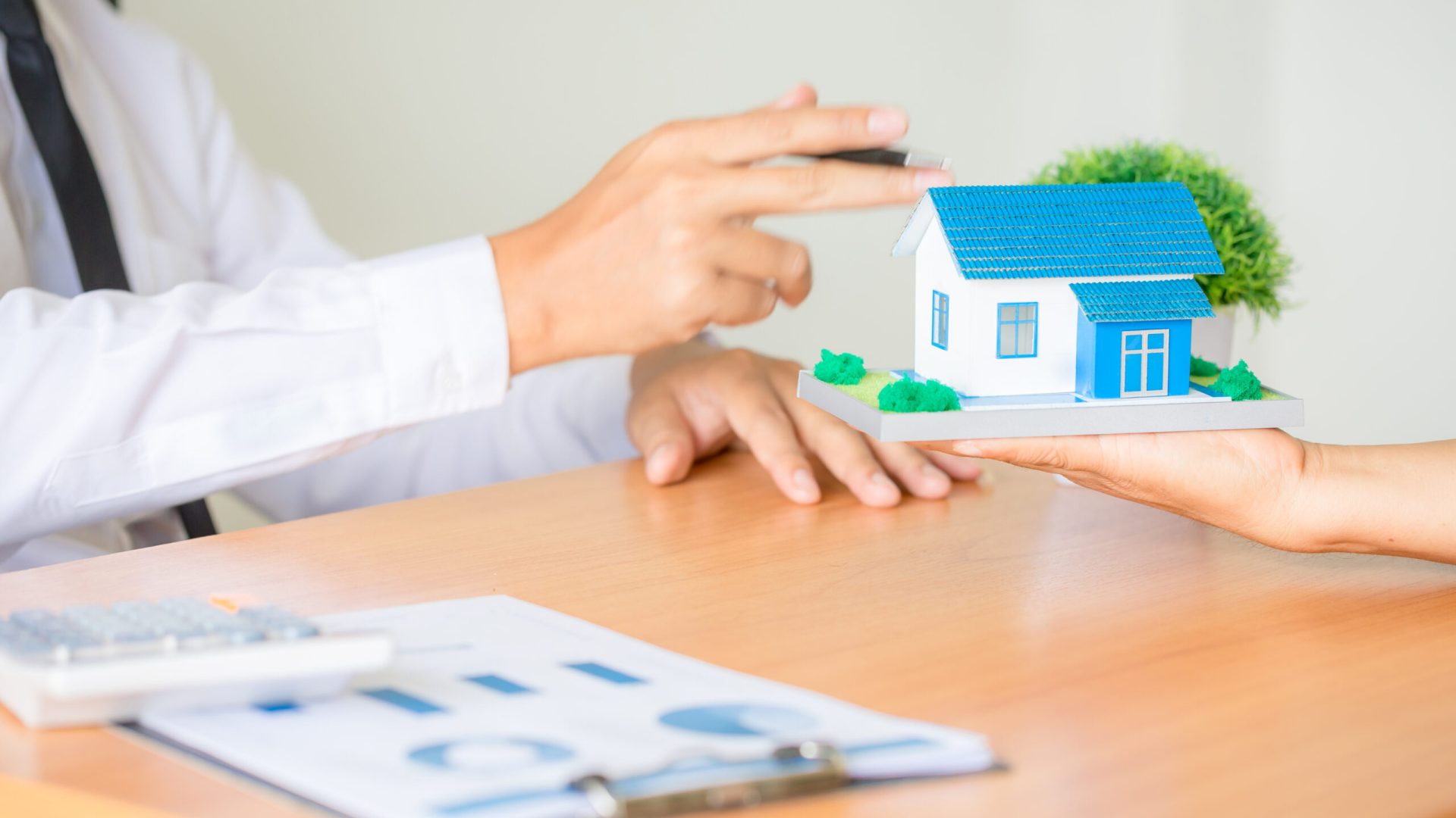 Real estate broker agent presenting and consult to customer to decision making sign insurance form agreement, home model, concerning mortgage loan offer for and house insurance.